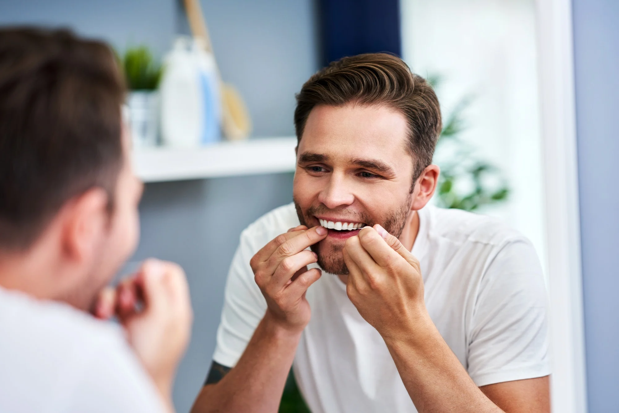 Adult man flossing teeth in the bathroom